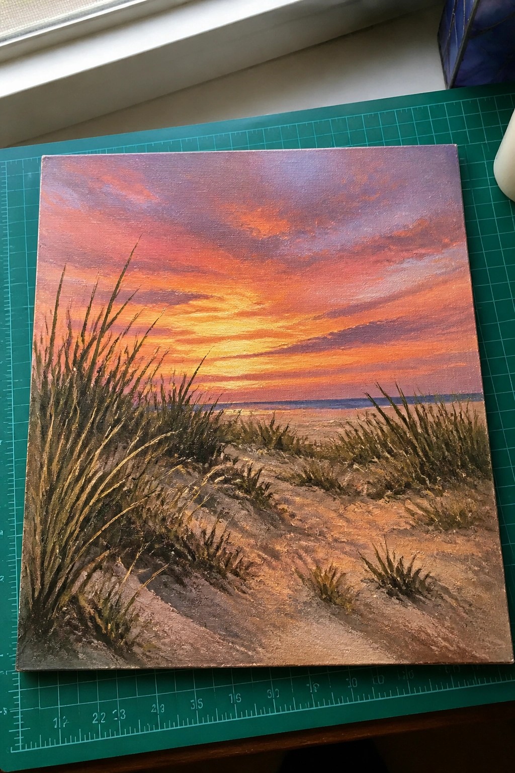 Vibrant sunset painting over ocean with foreground dunes and tall beach grass