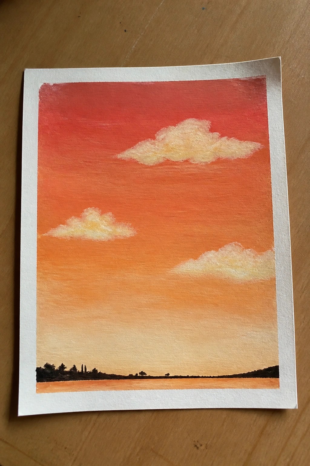 Watercolor painting of red-orange sunset sky with yellow clouds over dark landscape silhouette.