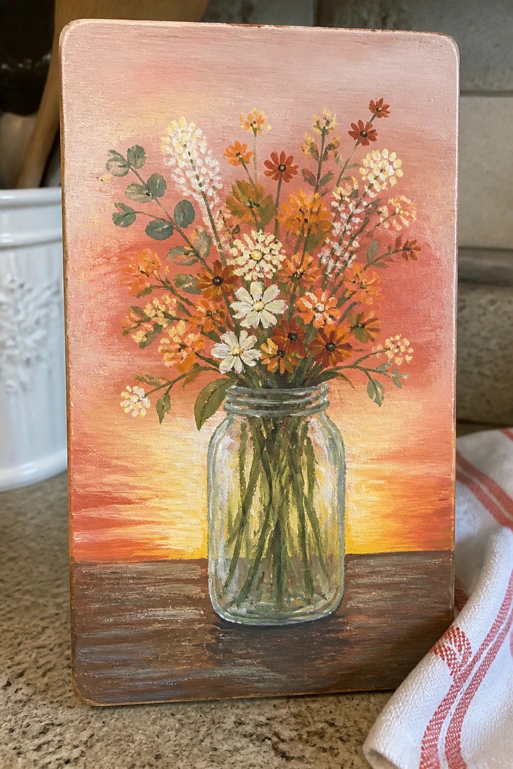 Vibrant wildflowers in glass jar against colorful sunset on wooden board painting