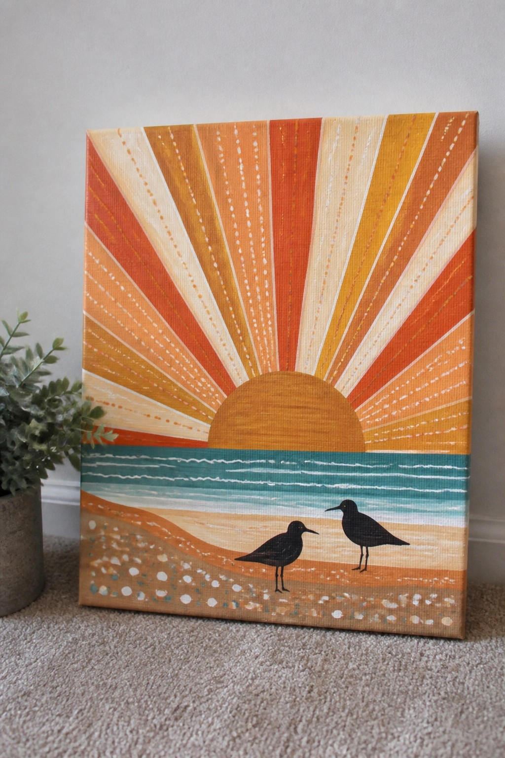 Vibrant sunset painting with radiating rays, teal waves, and two black birds on sand.