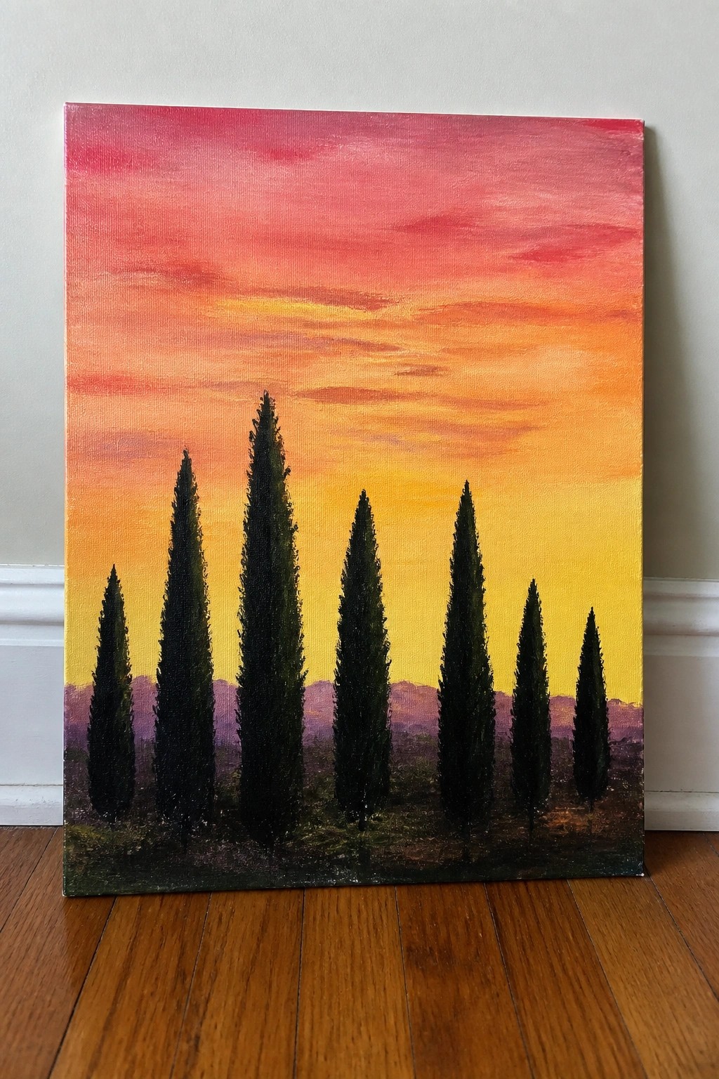 Vibrant sunset painting with silhouetted tall trees against pink orange yellow sky on canvas