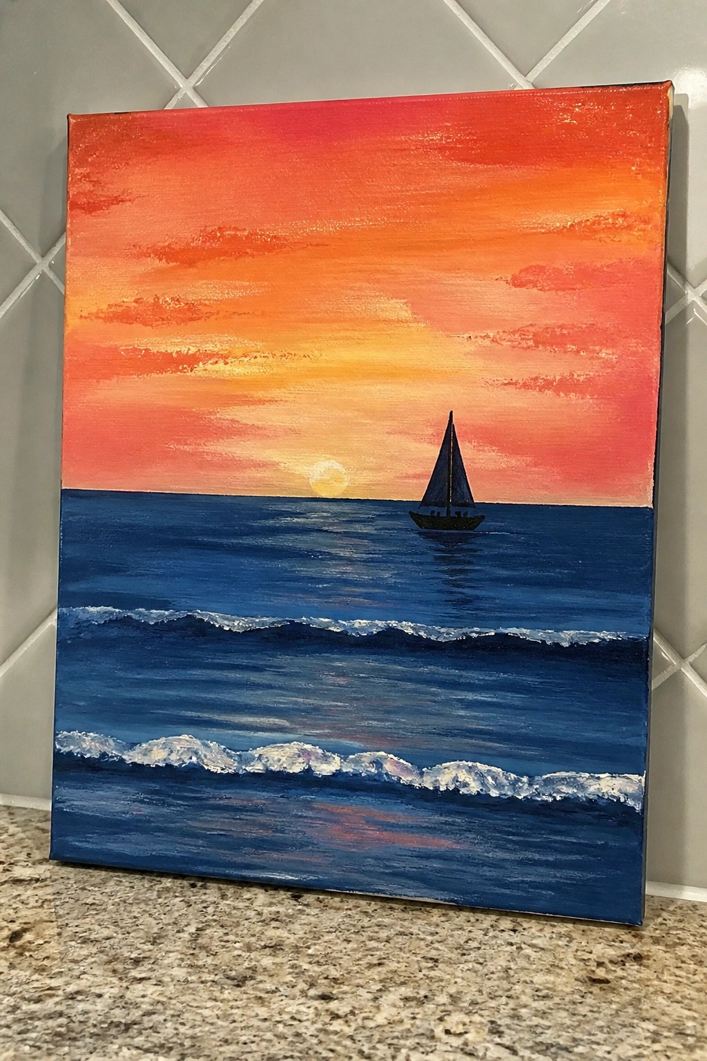 Sailboat on dark blue ocean waves under vibrant red-orange sunset sky with yellow sun.