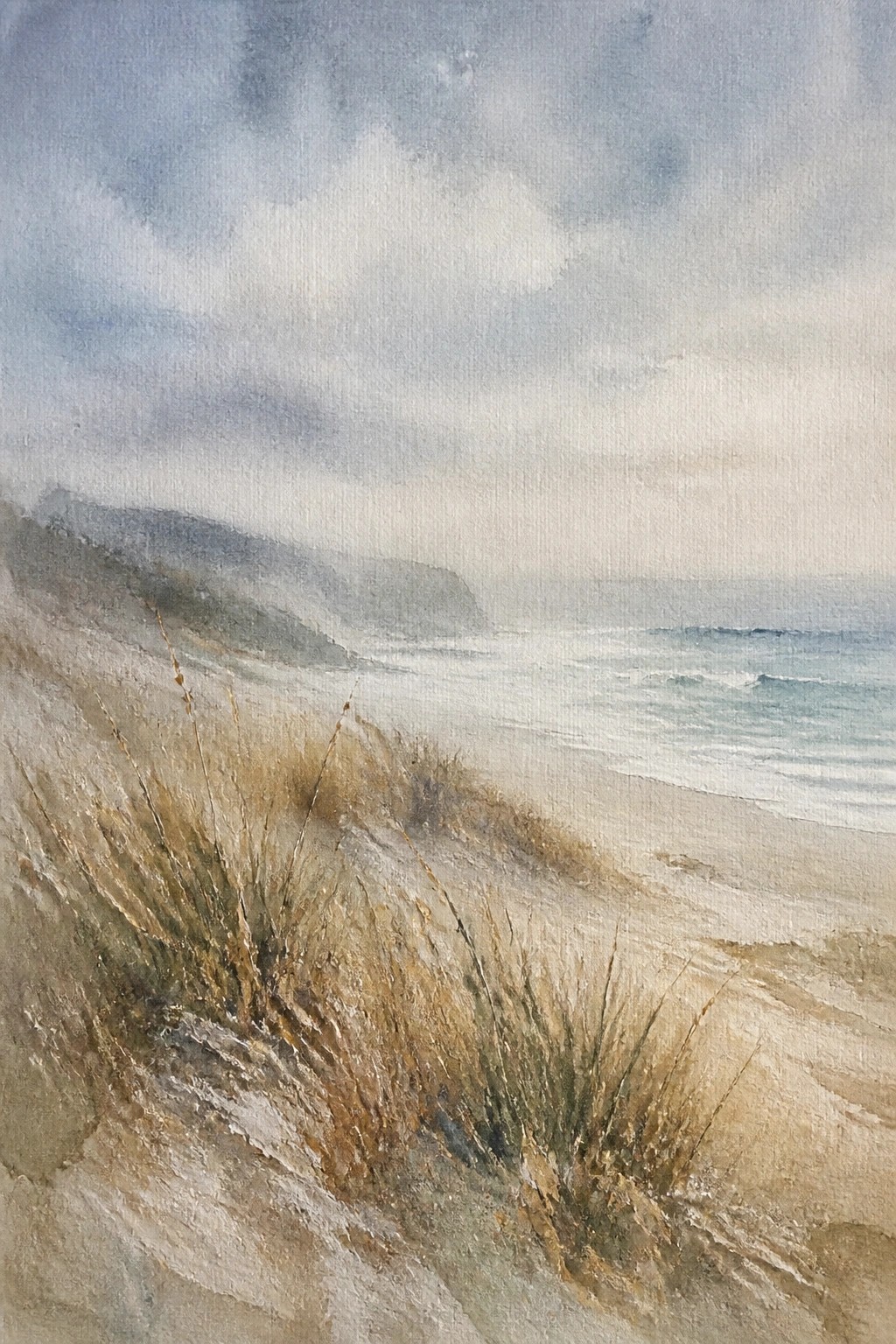 Watercolor painting of misty beach dunes with sea grass ocean waves and hazy hills under cloudy skies