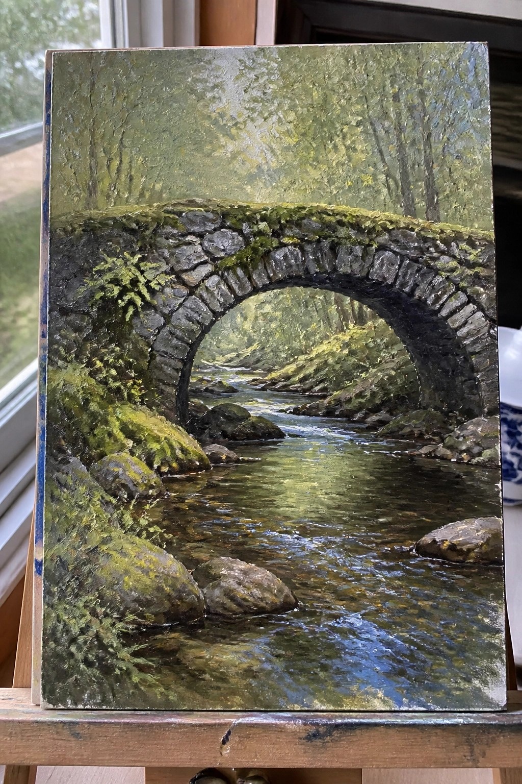 Mossy stone arch bridge over rocky stream in lush green forest painting