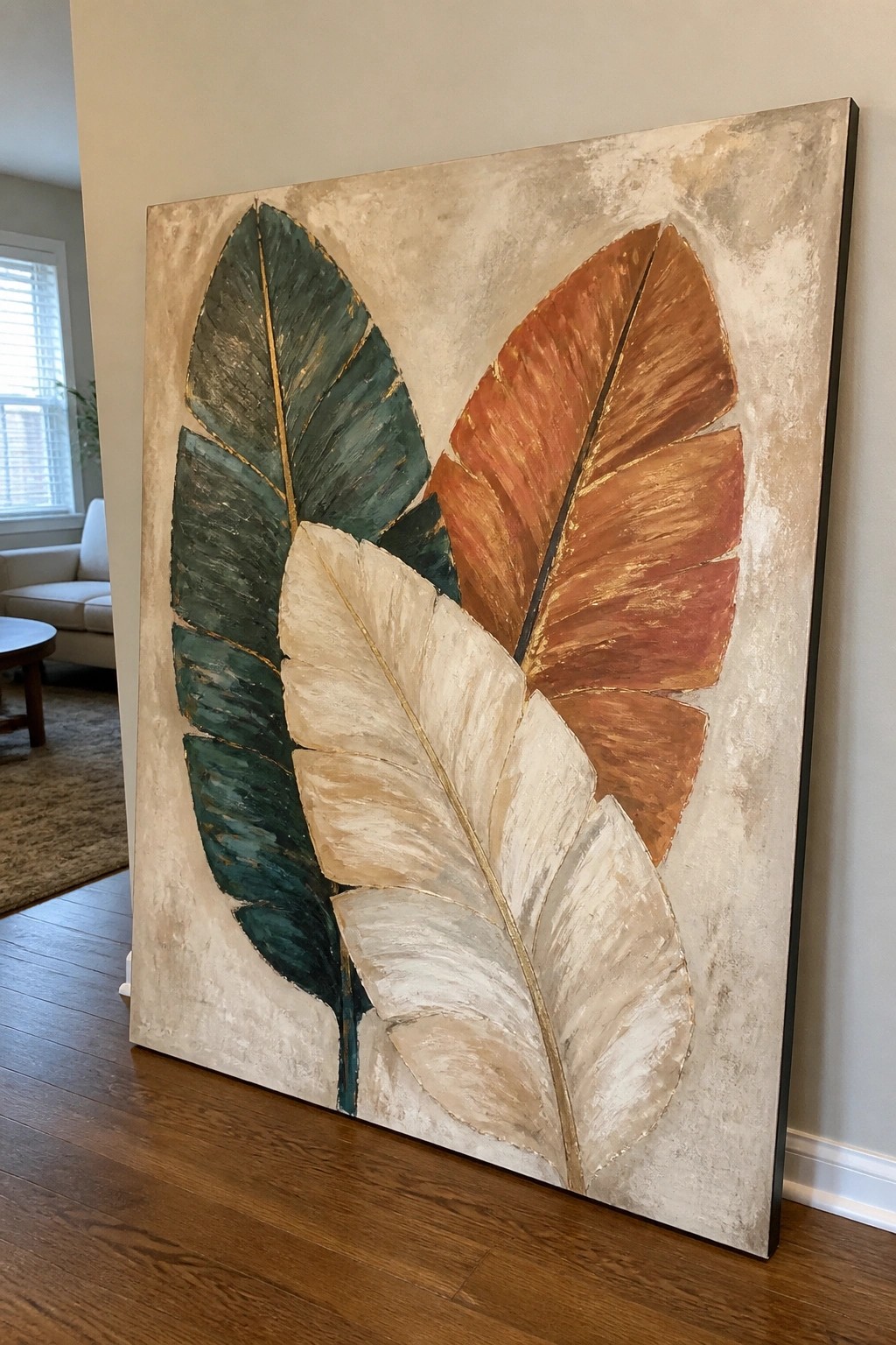 Large abstract painting of three tropical leaves in green, cream, and rust with gold accents.