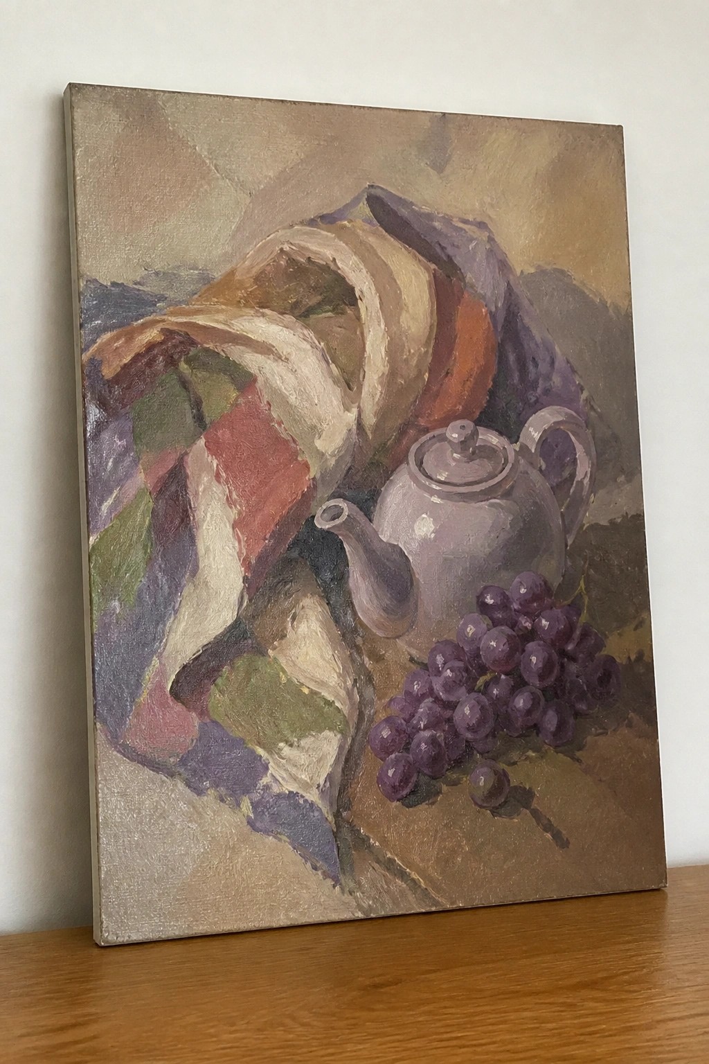 Still life with plaid drapery, purple teapot, and bunch of grapes.
