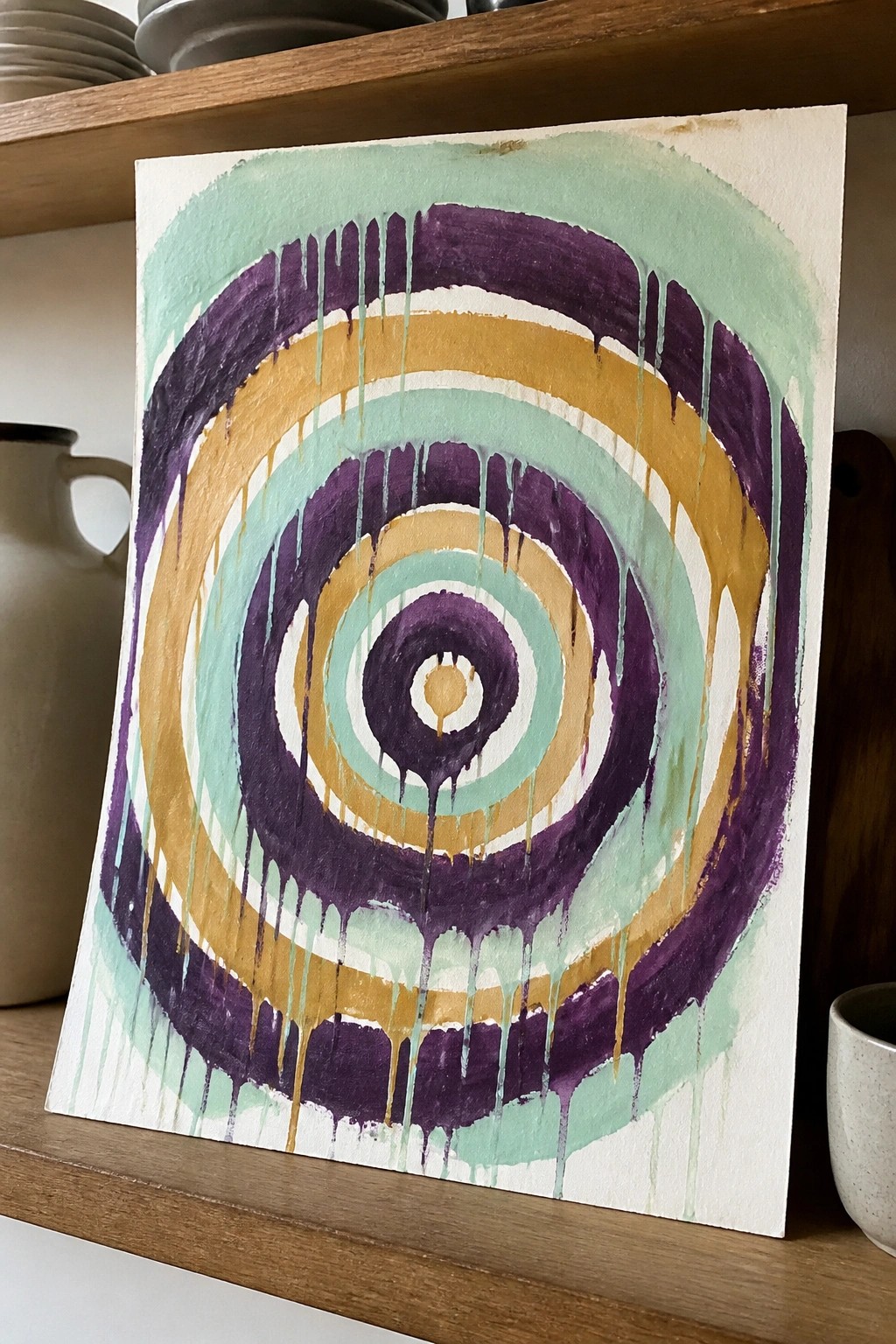 Abstract painting of dripping concentric circles in purple, gold, and teal.