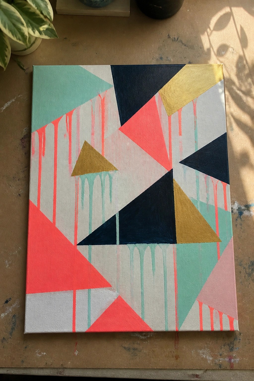 Abstract geometric canvas with colorful triangles and dripping paint on wooden table