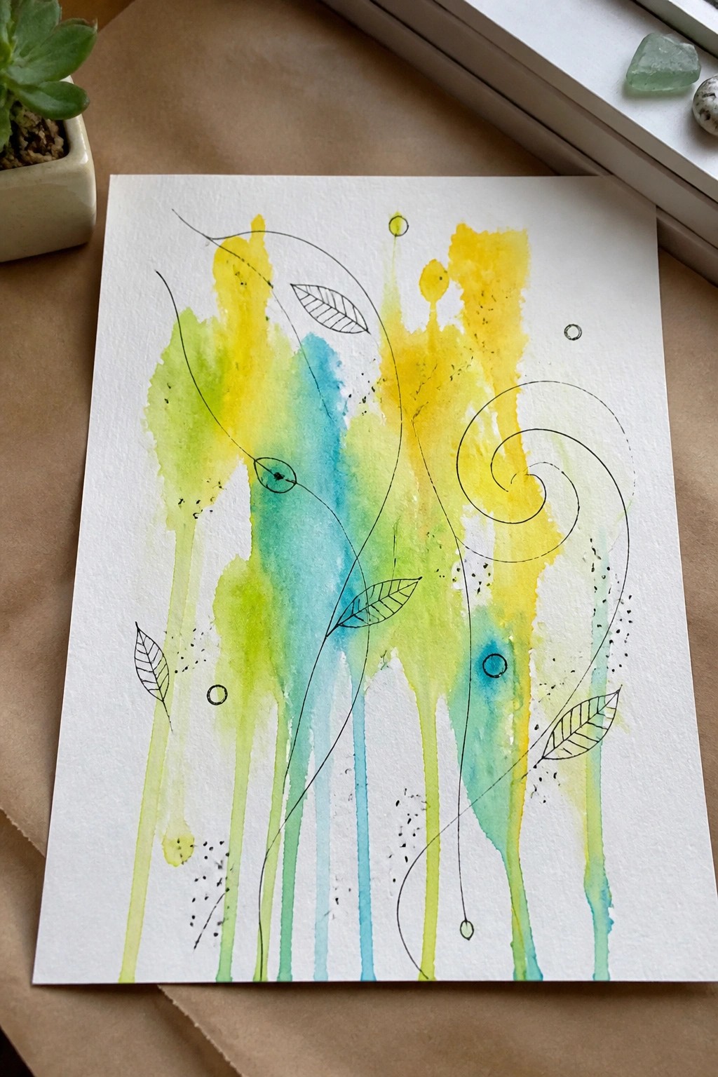 Abstract watercolor with yellow green blue drips, black leaf drawings, and swirling lines.
