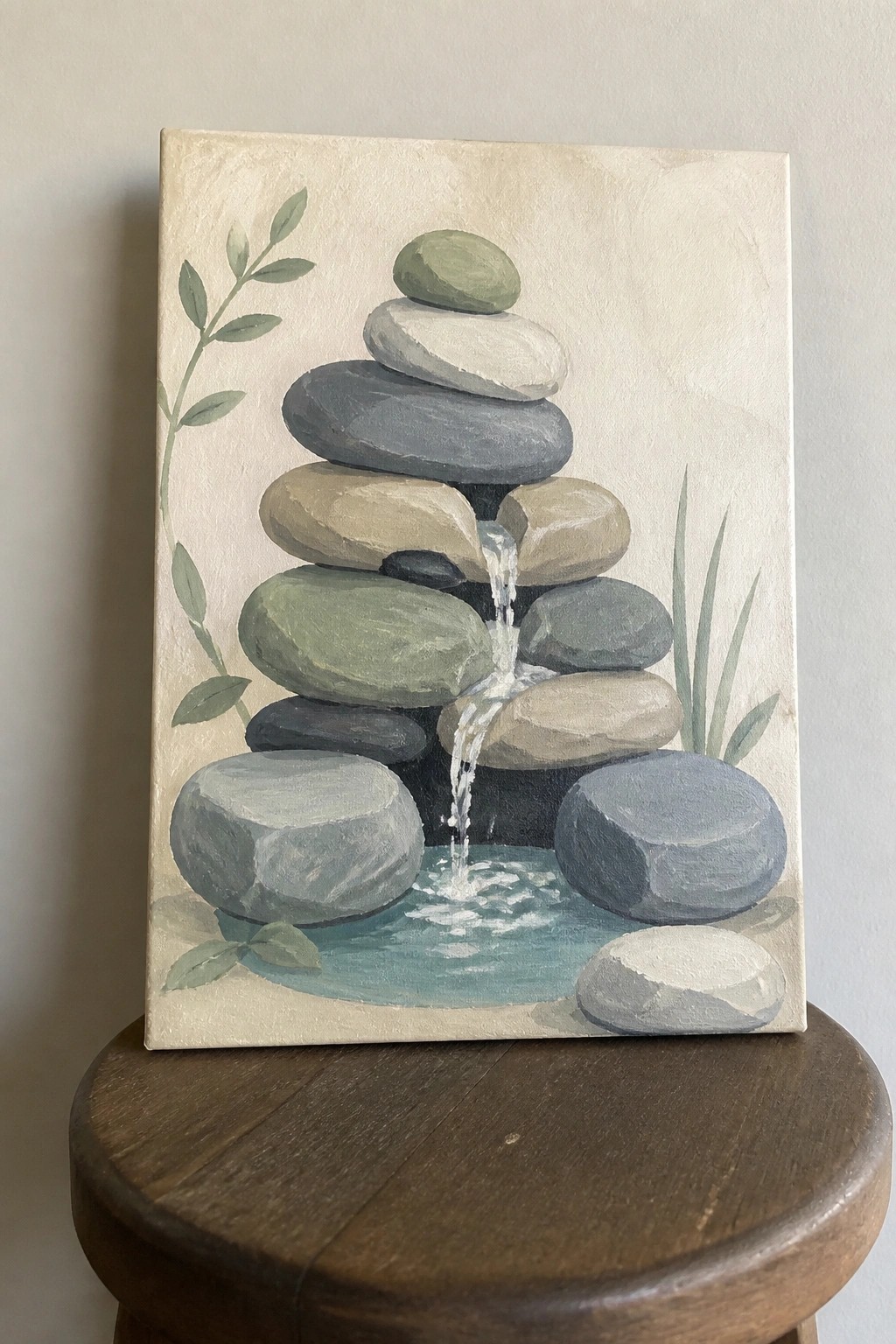 Painting of stacked stones with cascading water into pool and green leaves on wooden stool