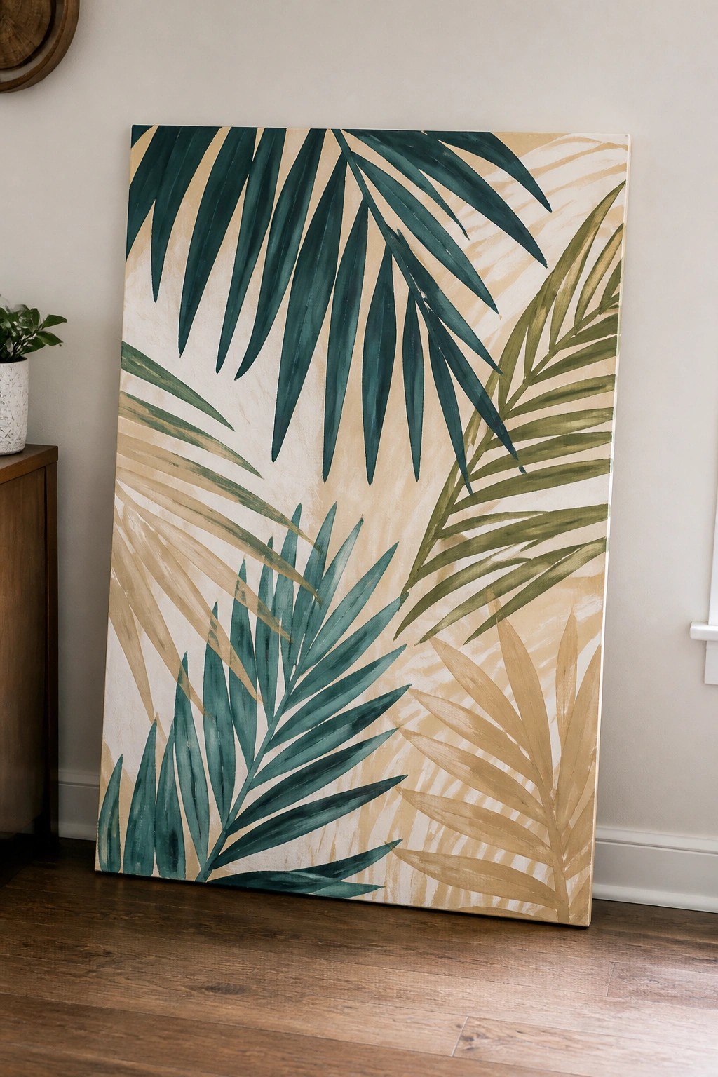 Large canvas painting of tropical palm leaves in green and beige tones leaning on wall