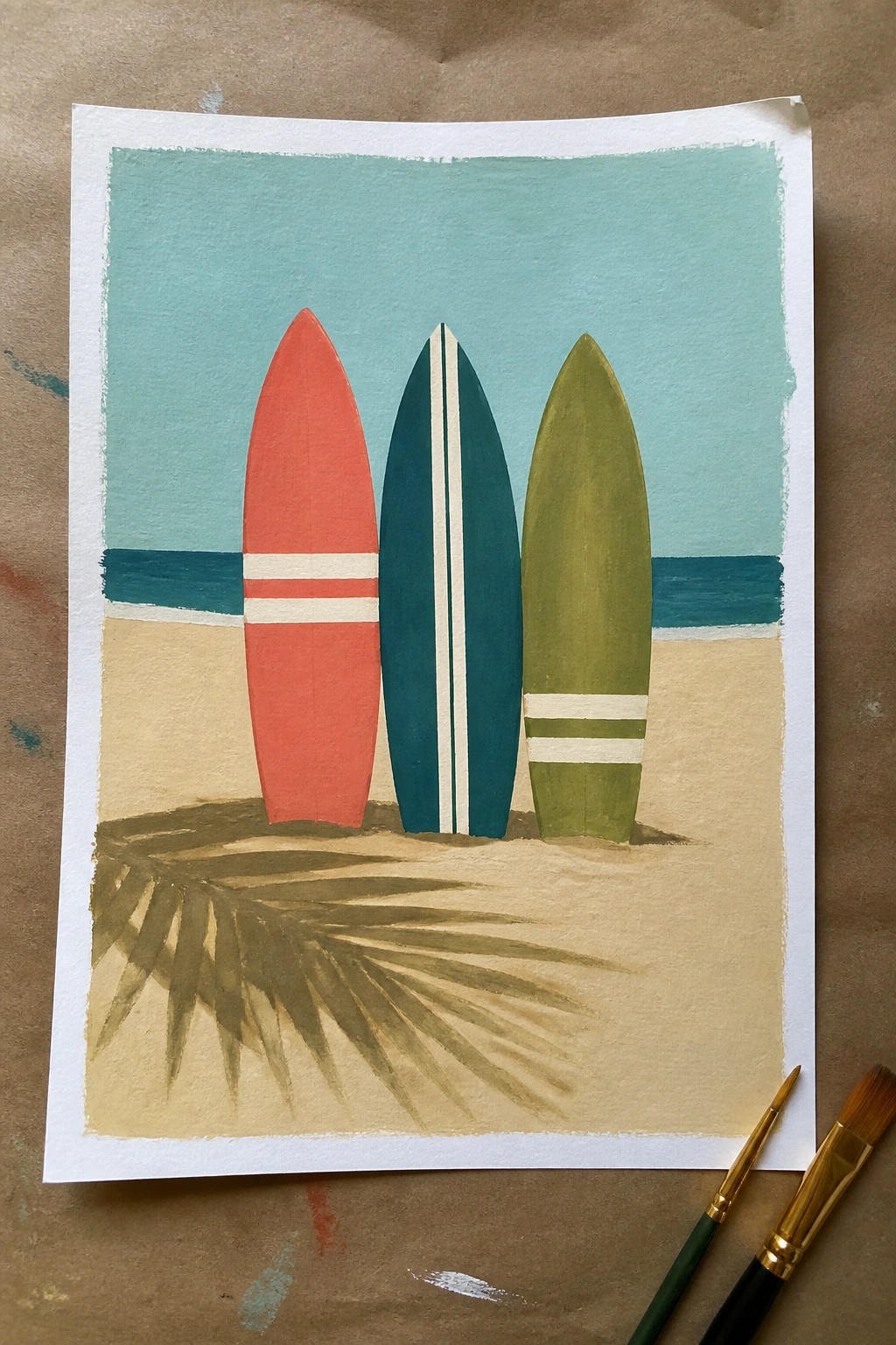 Three colorful surfboards on beach sand with palm frond shadow and ocean horizon.
