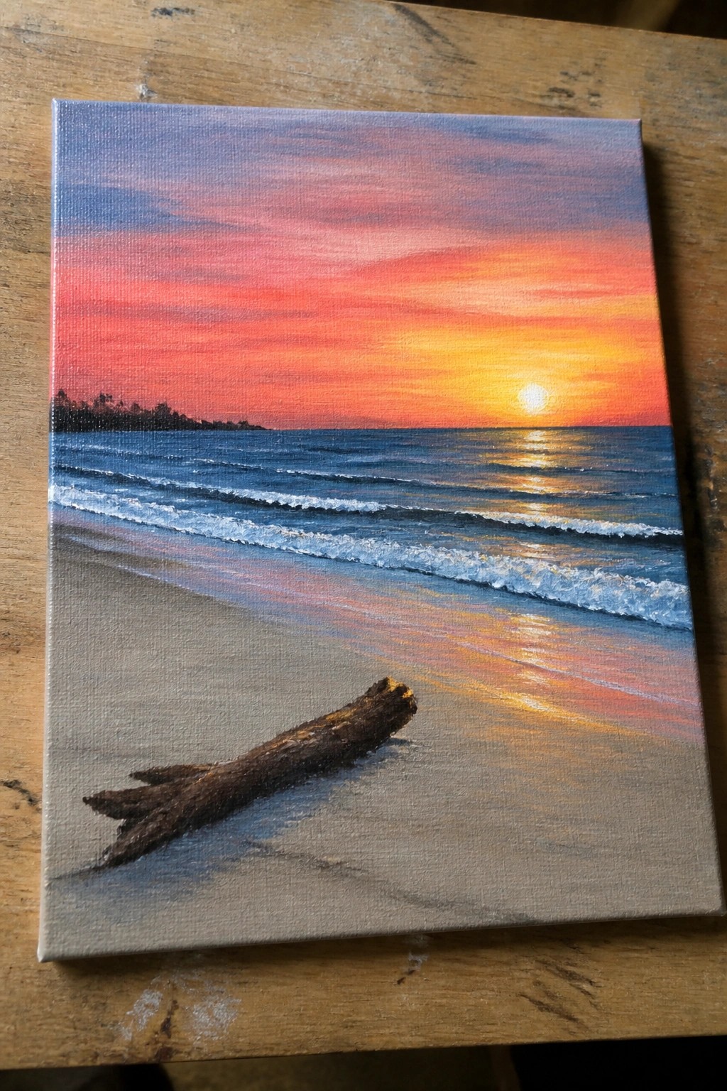 Vibrant sunset over ocean with colorful sky, waves, and driftwood on sandy beach