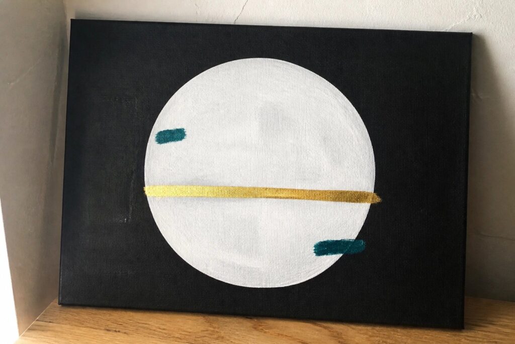 20 Black Canvas Acrylic Painting Ideas With Dramatic Modern Edge Abstract painting: white circle with gold line on black canvas, teal accents on wood.