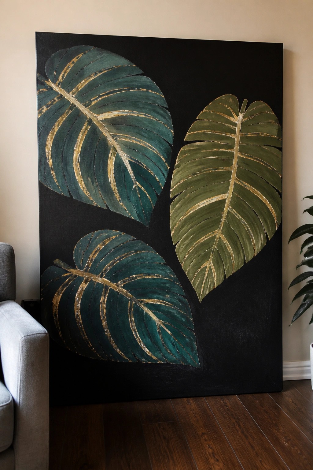 Large painting of three green and gold monstera leaves on black canvas in room