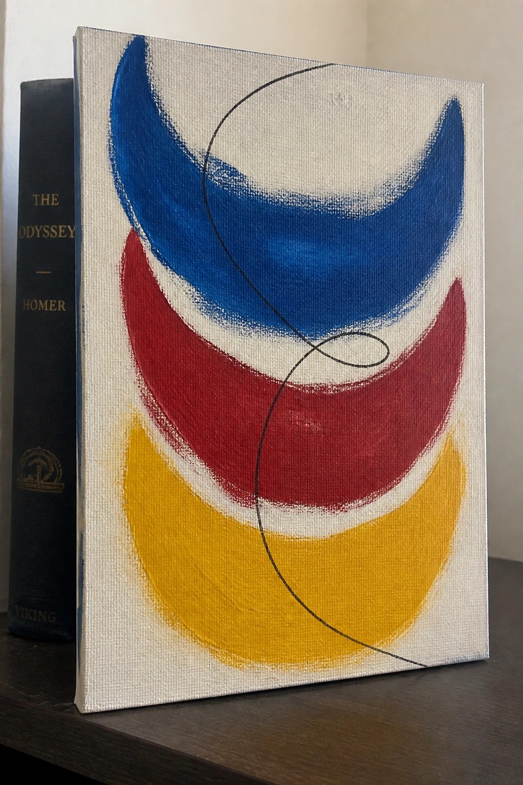 Abstract painting with blue red yellow crescents, black curving line, beside The Odyssey book