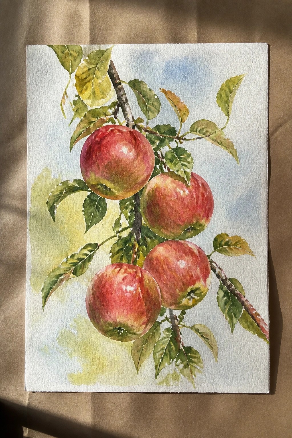 Watercolor painting of four red apples on a leafy tree branch