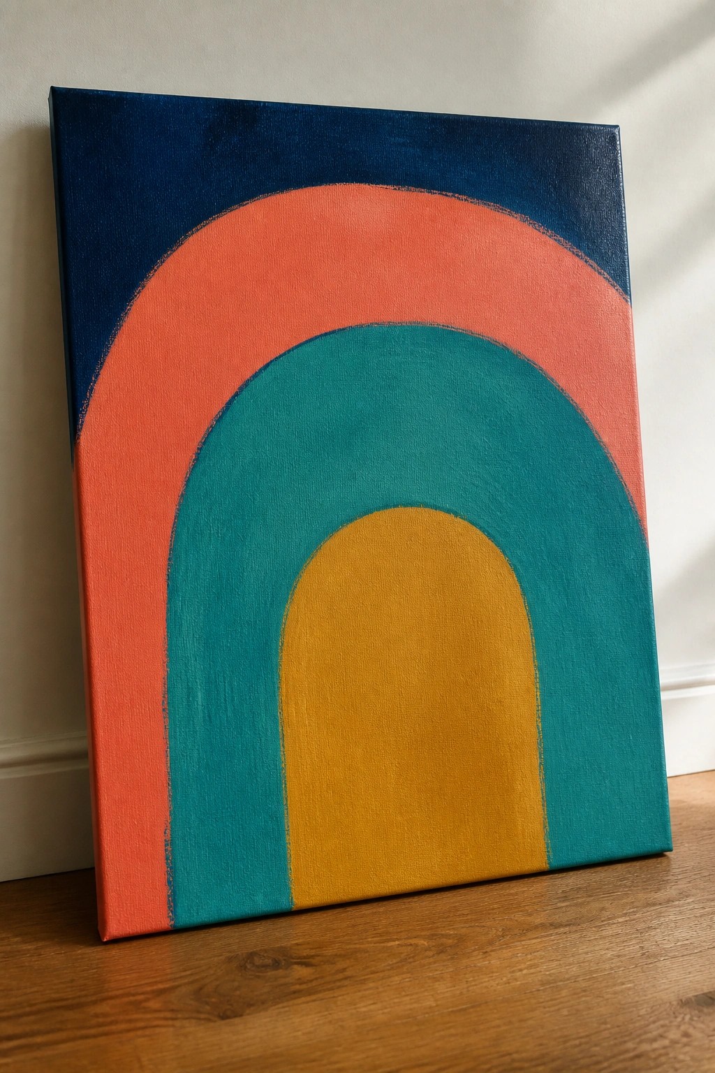 Abstract canvas with nested arches in navy, coral, teal, and yellow leaning on floor.