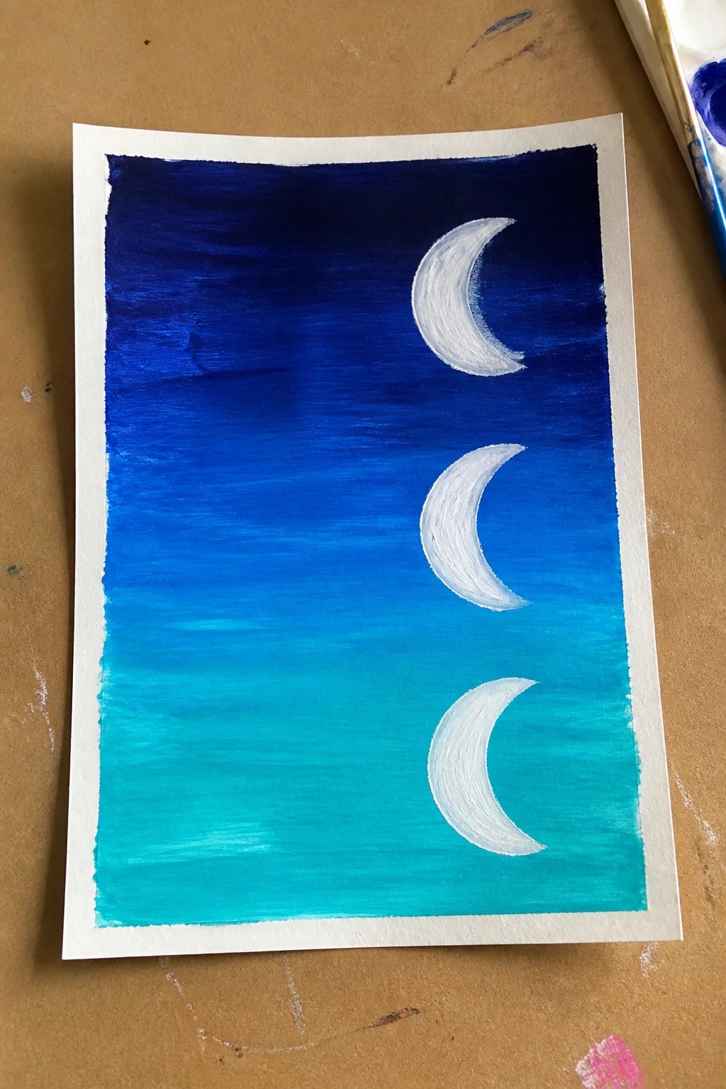 Three white crescent moons on a dark blue to turquoise gradient sky