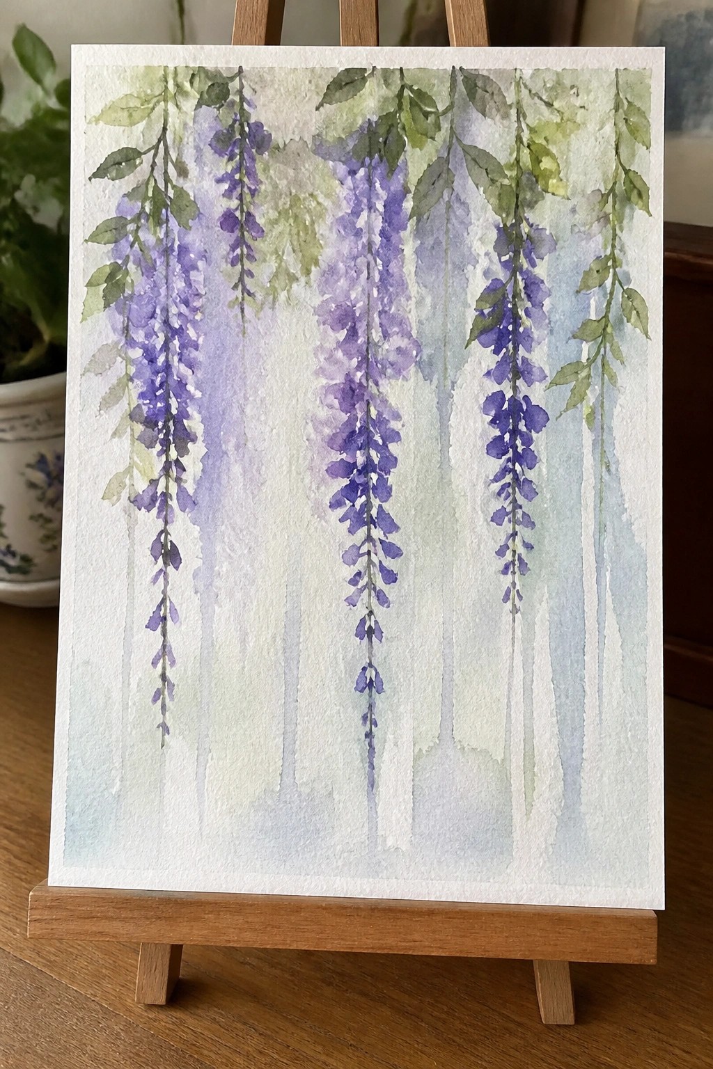 Watercolor painting of cascading purple wisteria flowers on wooden easel