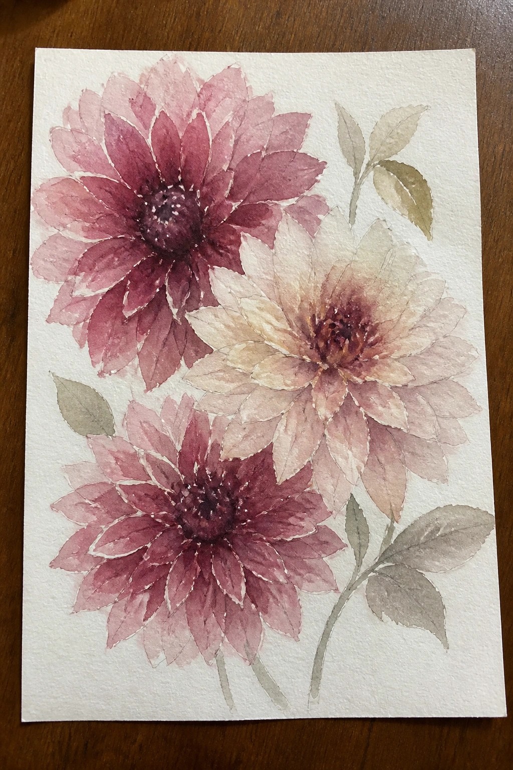 Watercolor painting of three pink and maroon dahlias with green leaves on paper