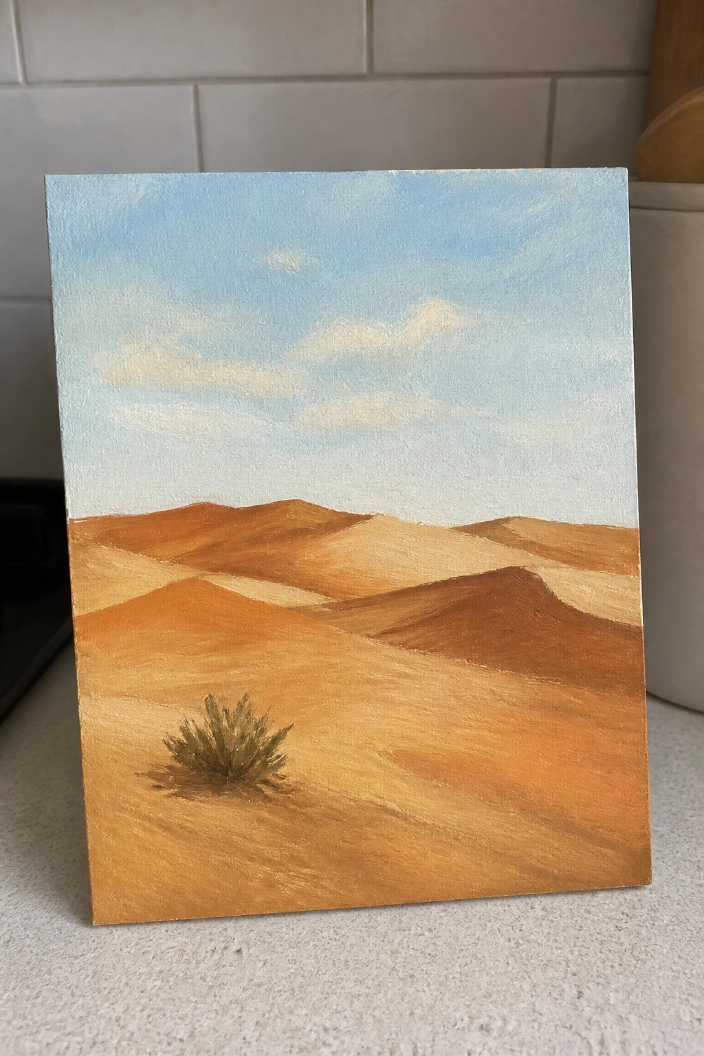 Orange sand dunes under blue sky with small bush on canvas painting