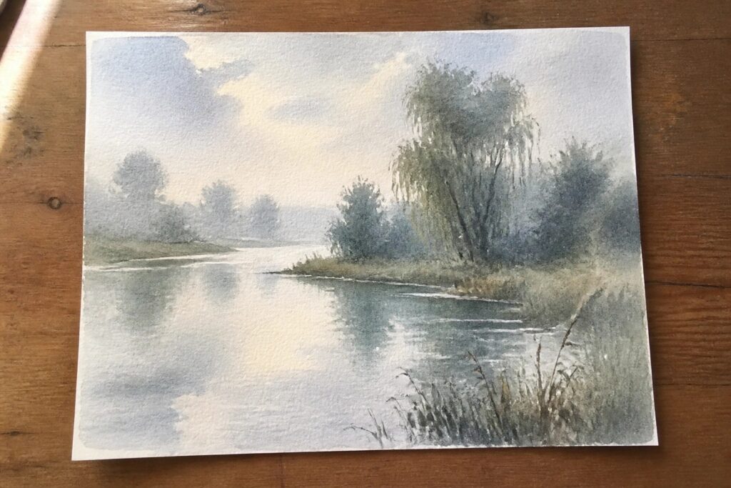 Watercolor of misty river with weeping willows reflecting on calm water and grass.