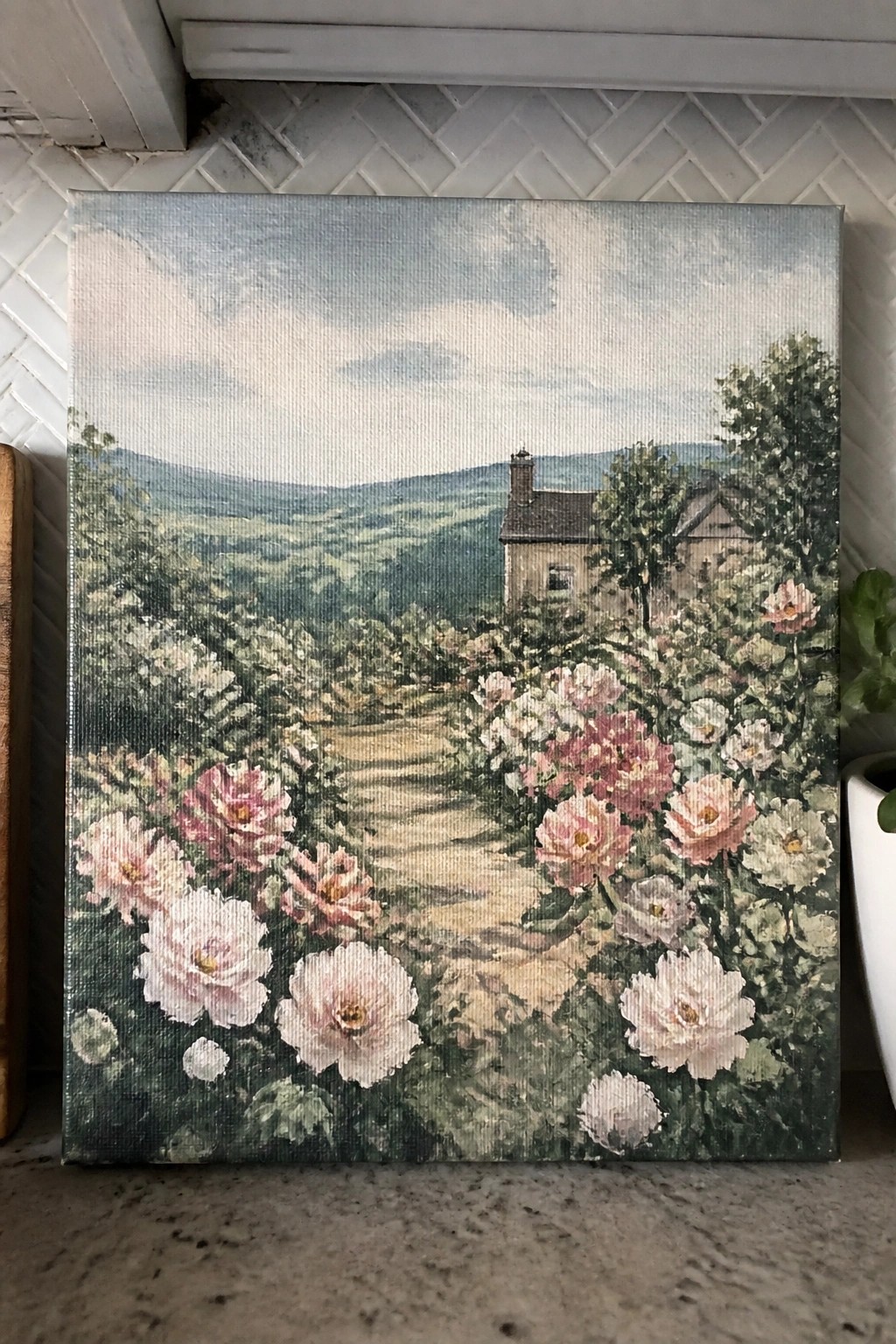 Oil painting of pink roses along a path to a stone house in hills
