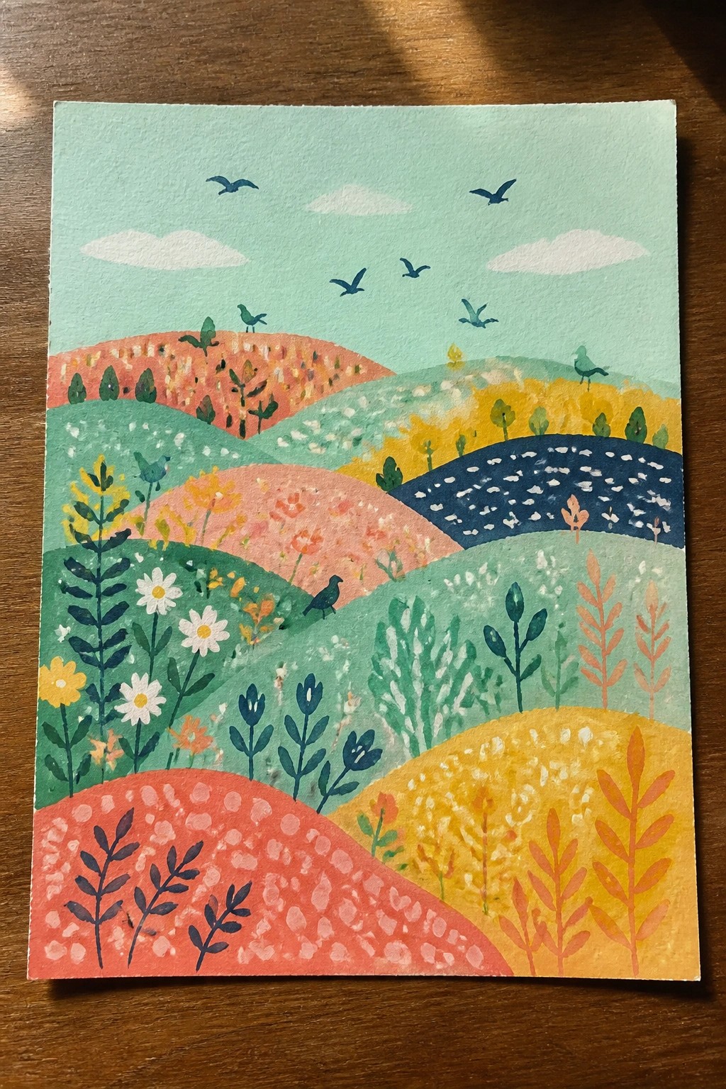 Colorful watercolor landscape of rolling hills with flowers, trees, and flying birds.