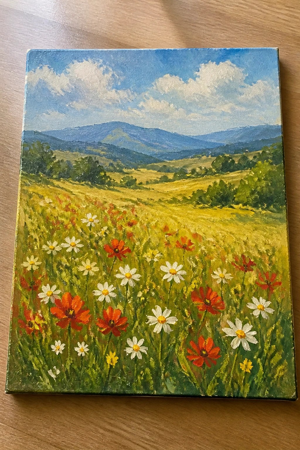 Vibrant wildflower meadow with red poppies, white daisies, and distant blue mountains