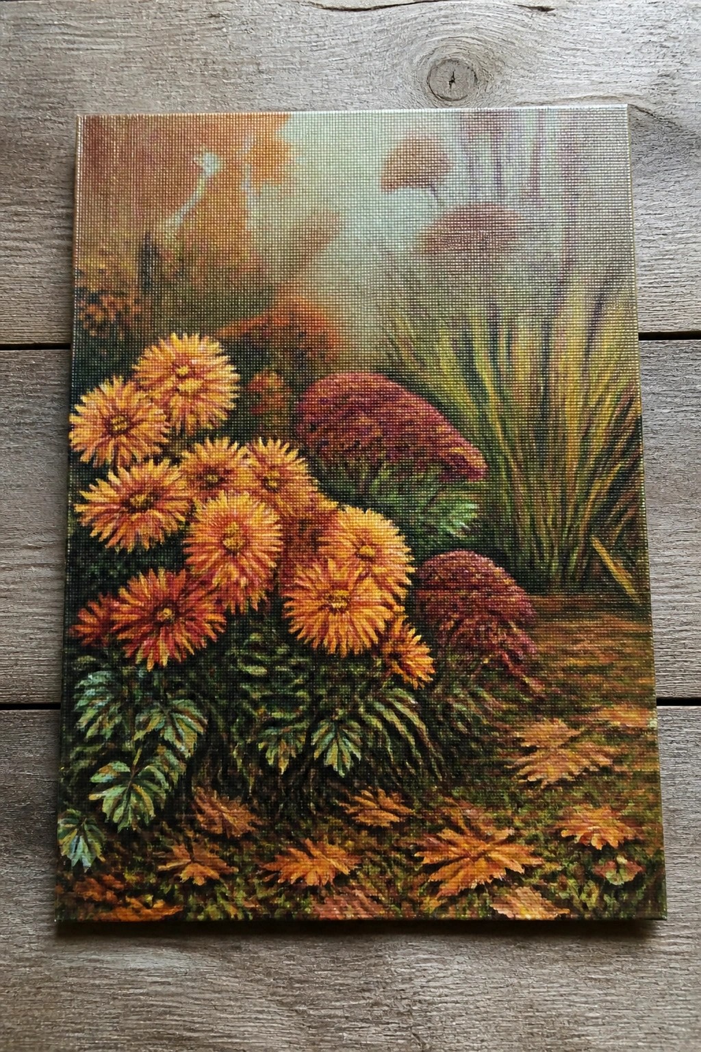 Vibrant orange chrysanthemums and red foliage amid autumn leaves in misty woods