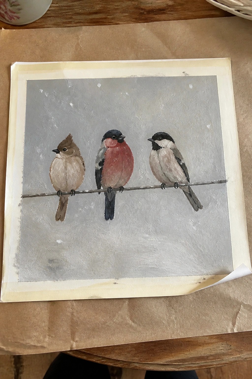 Three birds perched on wire: brown, red-breasted, black-and-white, against gray background.