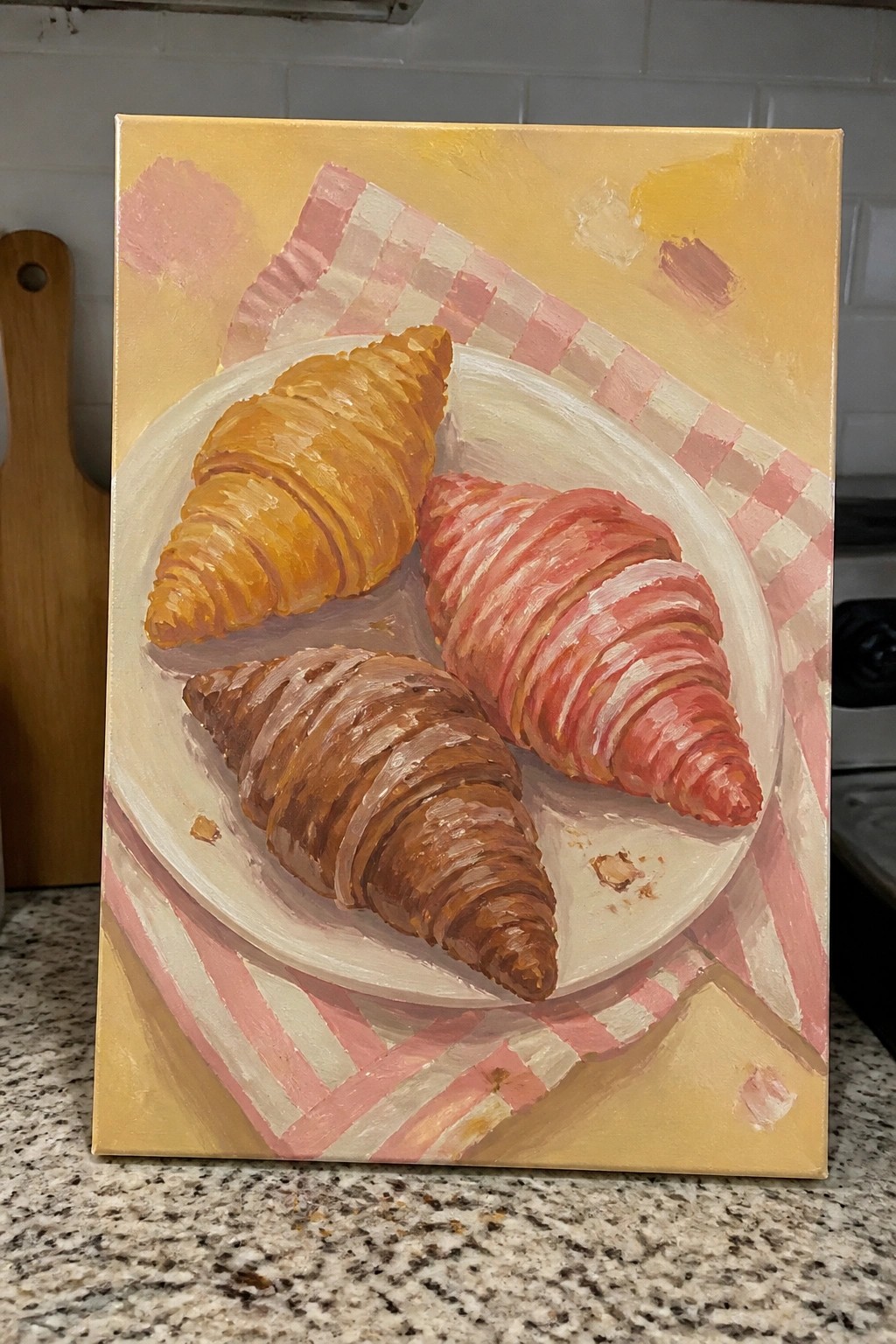 Three croissants on a white plate over pink checkered cloth in oil painting.