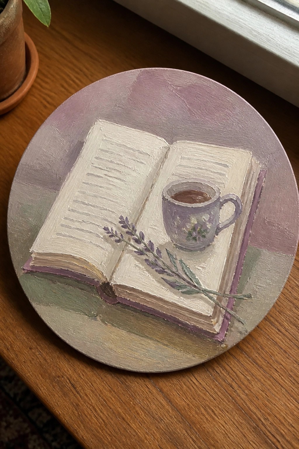 Still life painting of open book with teacup and lavender on round canvas.