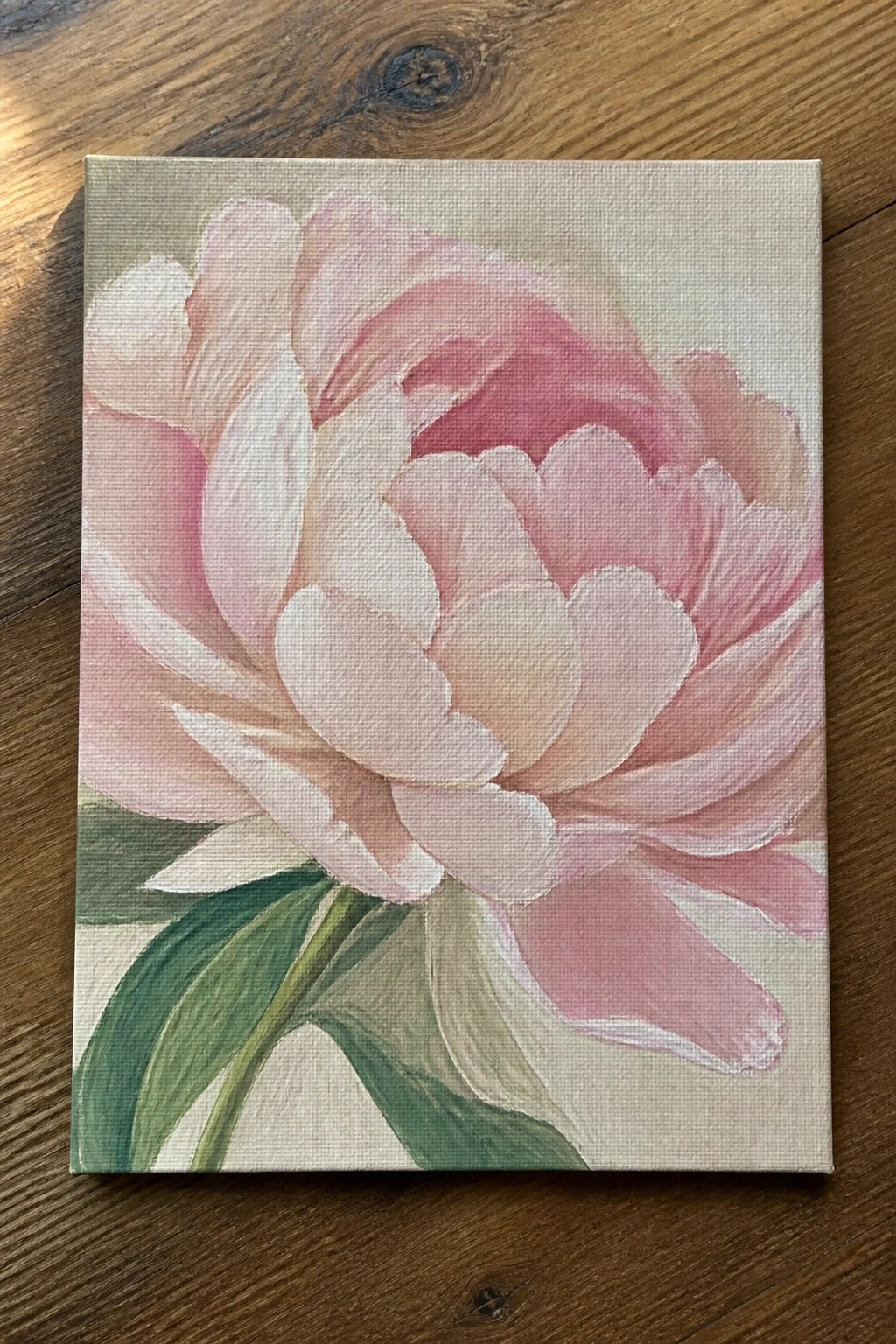 Pink peony flower painting with layered petals and green leaves on canvas.