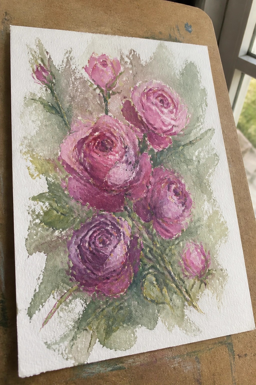 Watercolor painting of vibrant pink roses with green leaves and gold accents