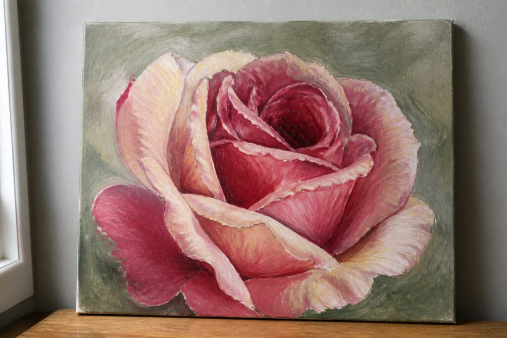 20 Romantic Rose Flower Painting Ideas in Realistic and Impressionist Styles Realistic painting of blooming pink rose on textured green canvas atop wood