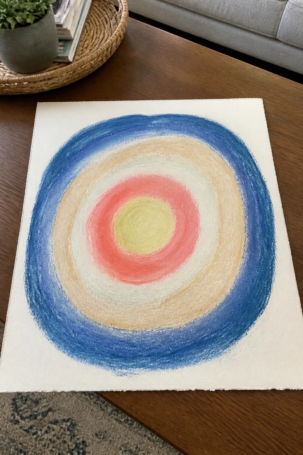Concentric circles in blue, beige, white, red, and yellow on paper atop wooden table.