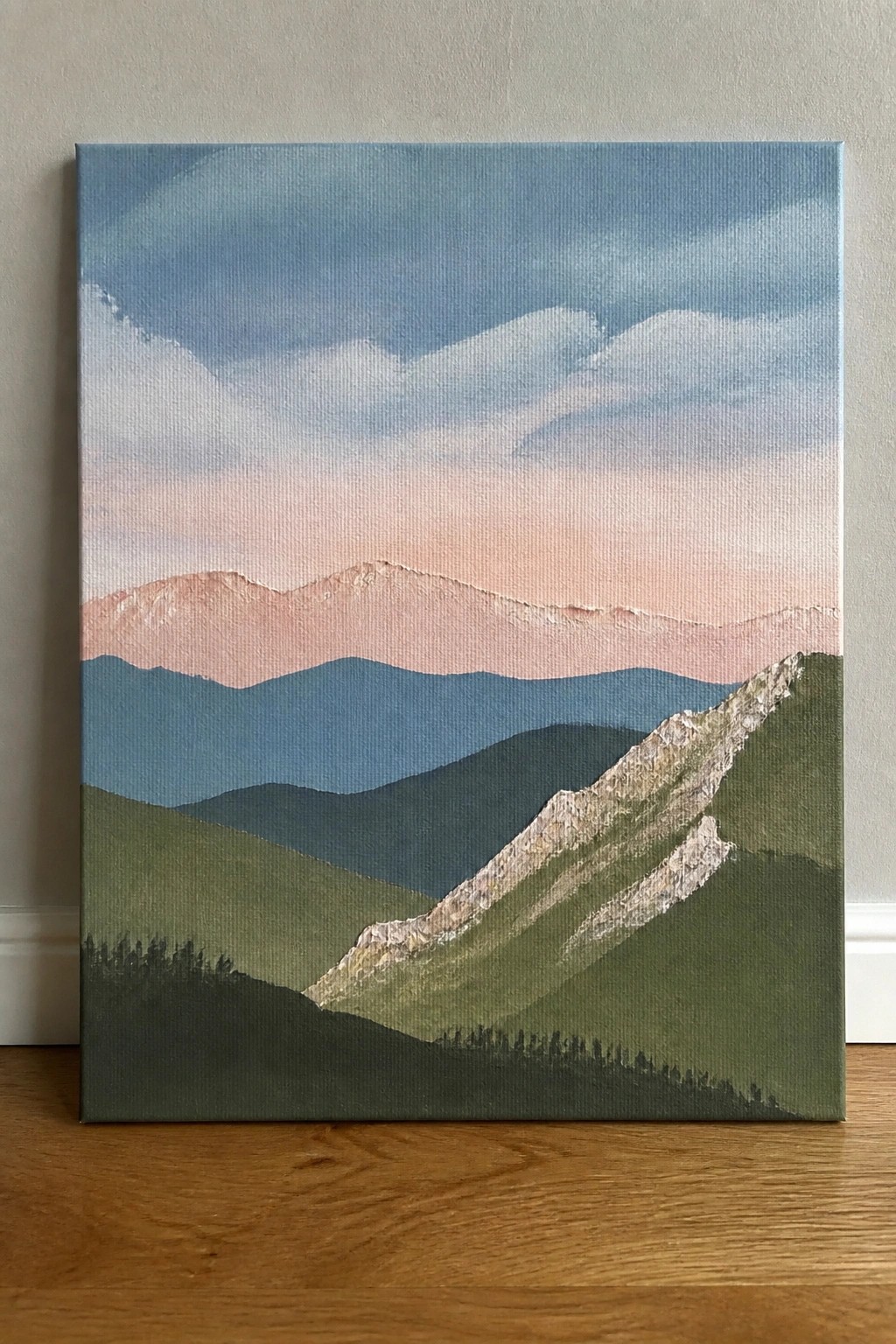 Layered mountain landscape painting with green hills, blue ridges, and pink peaks.