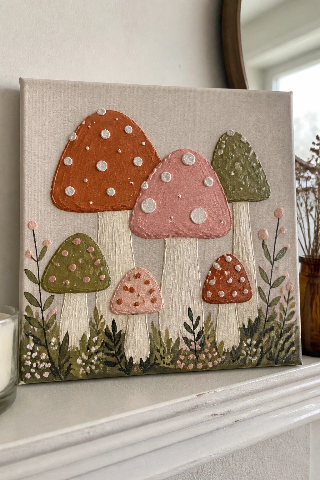 Textured canvas painting of colorful spotted mushrooms with leafy base on mantel