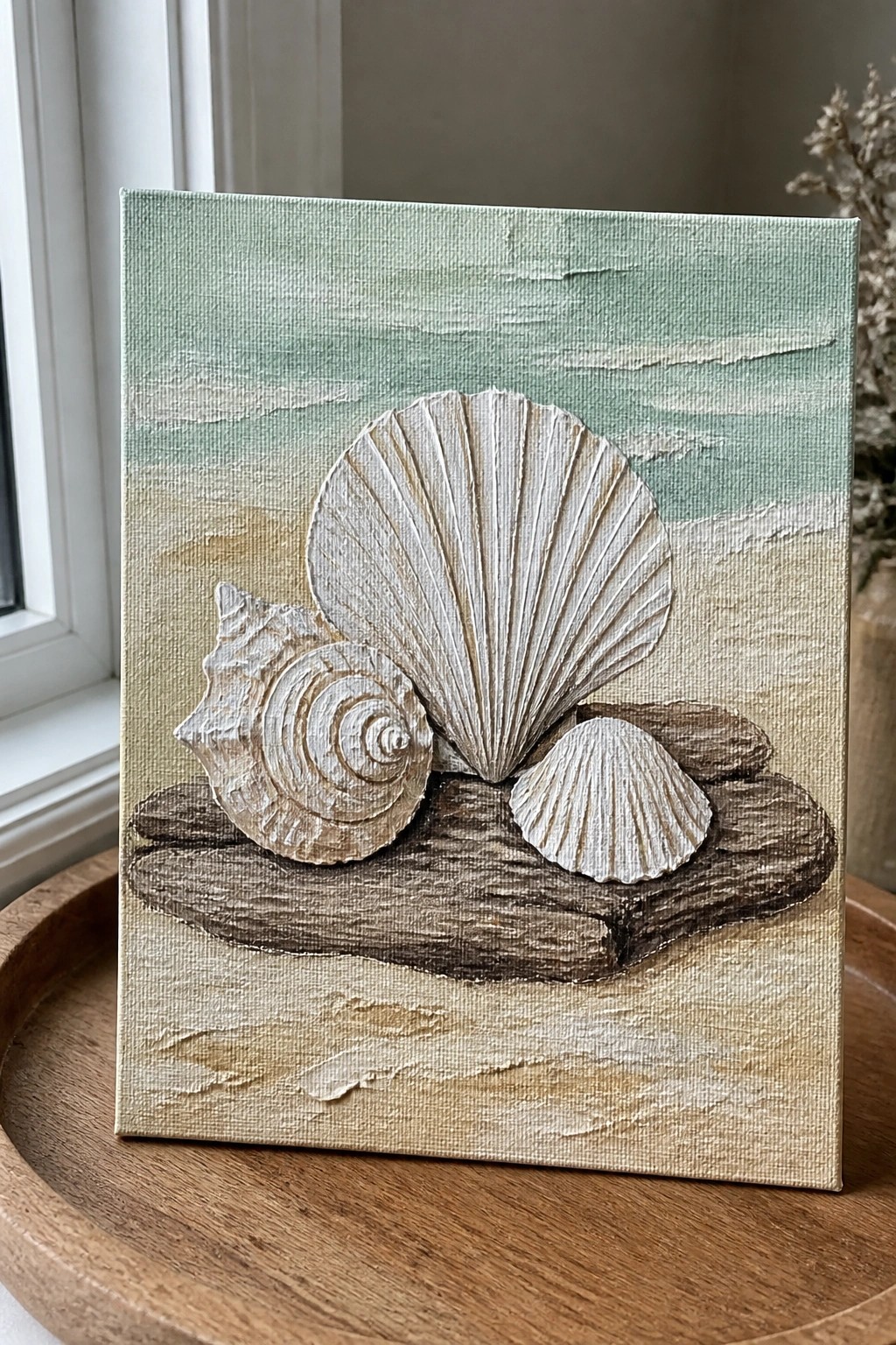 A textured painting shows three white seashells on brown driftwood against a background of sandy beige and soft turquoise waves.