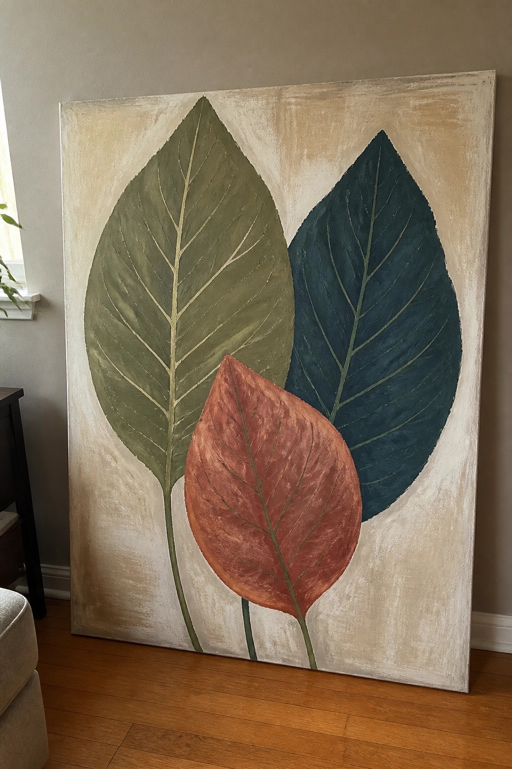 Abstract painting of three overlapping leaves in green, teal, and rust on beige canvas