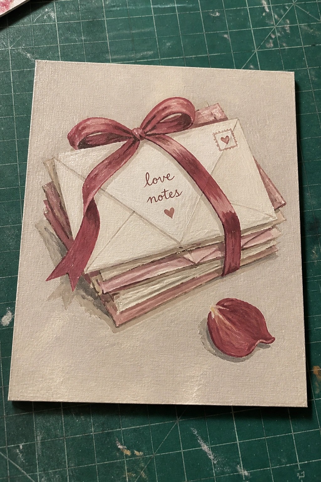 Stack of white envelopes tied with maroon ribbon bow labeled love notes beside rose petal