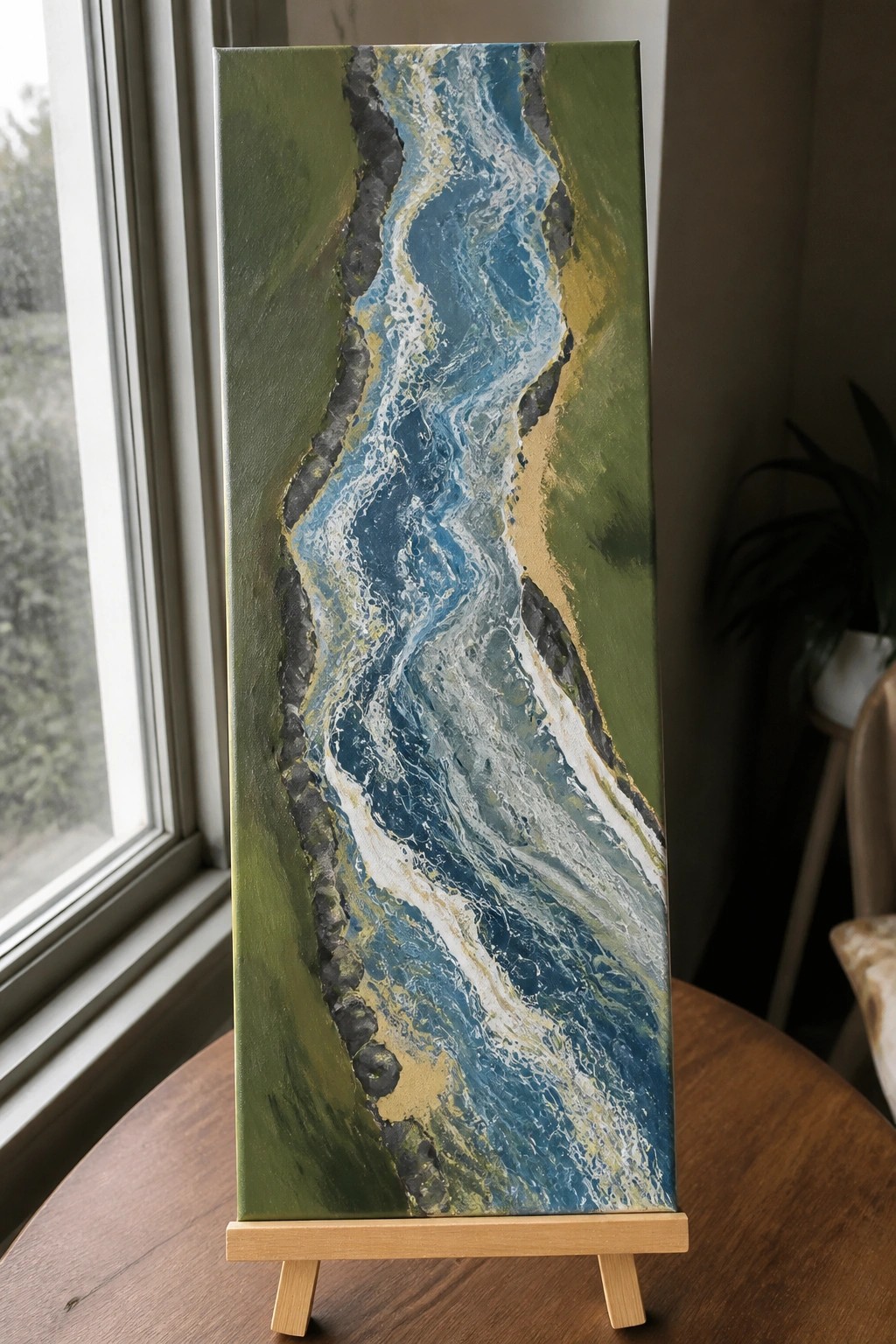 Abstract fluid art painting of winding blue river through green landscape on wooden easel