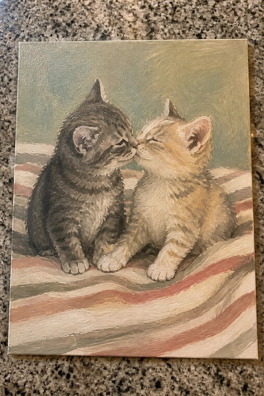 Dark gray and tan kittens touch noses on red striped fabric.