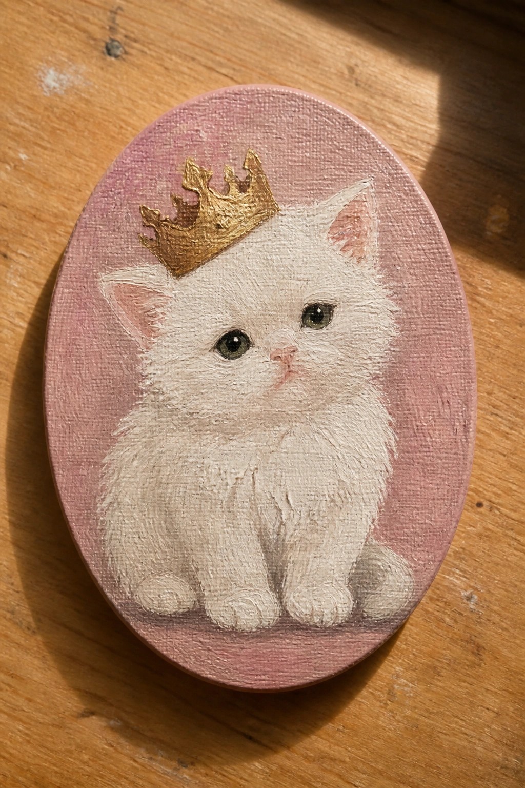 White kitten with gold crown on pink oval canvas painting