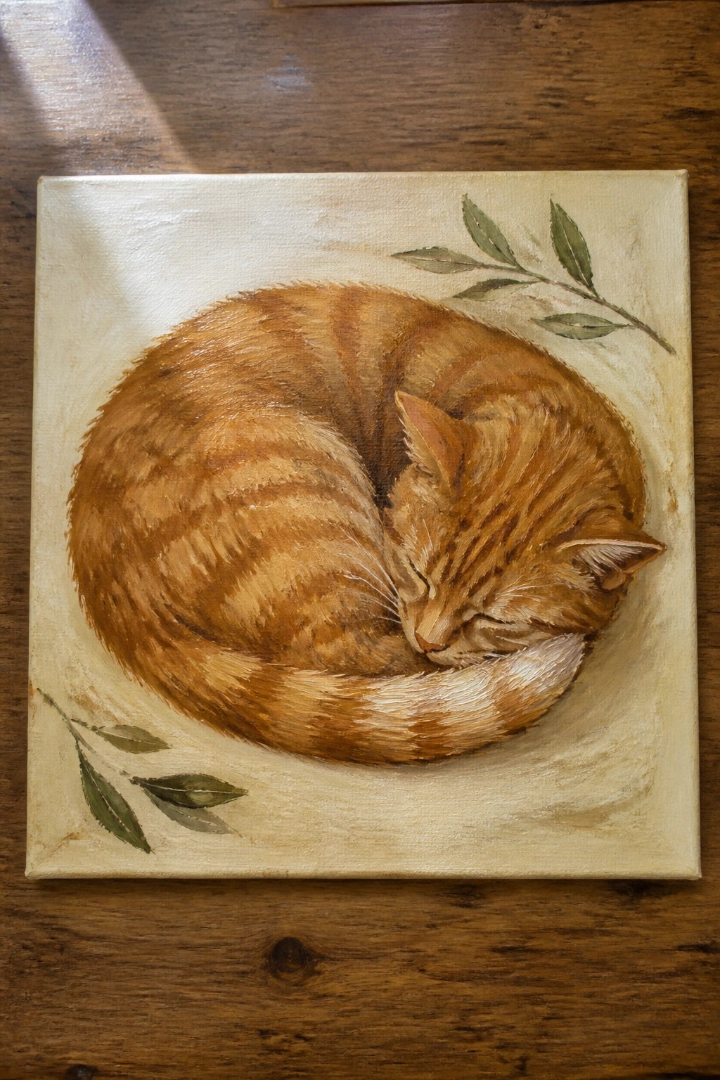 Orange tabby cat curled asleep on beige canvas with green leafy branches