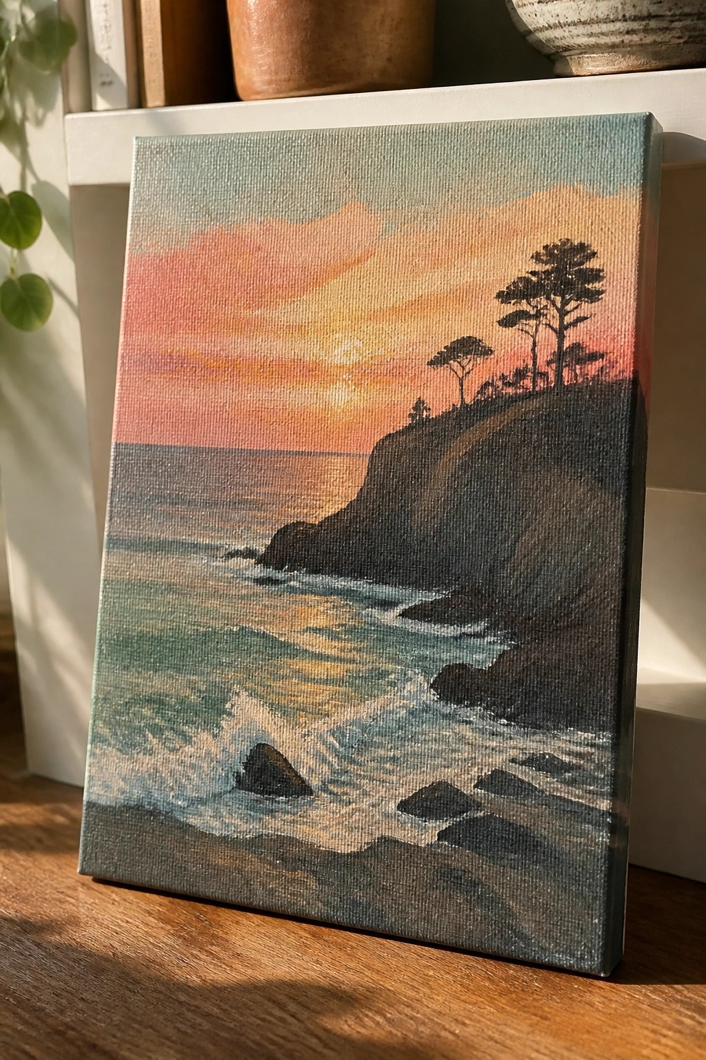 Seascape painting of sunset over ocean waves crashing on rocks below cliffside trees