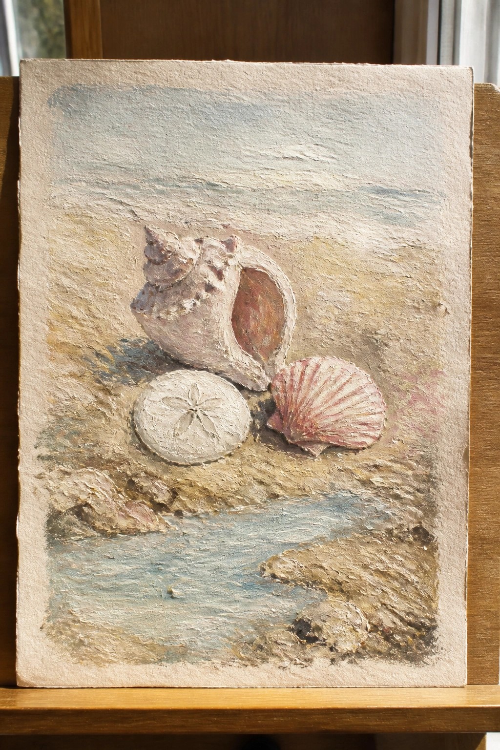 Textured painting of a conch shell, sand dollar, and scallop on a beach.