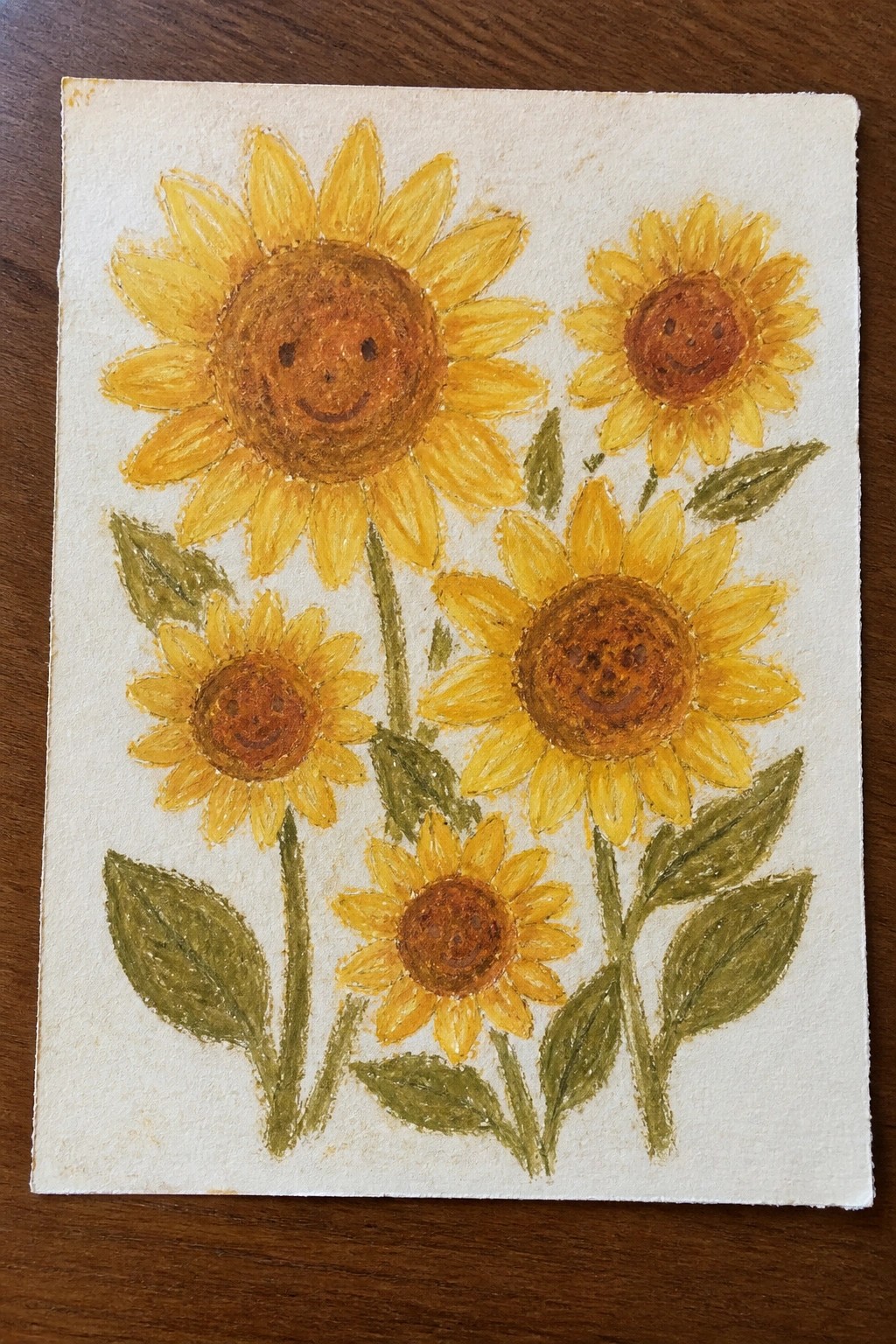Watercolor painting of five smiling sunflowers with yellow petals and green leaves